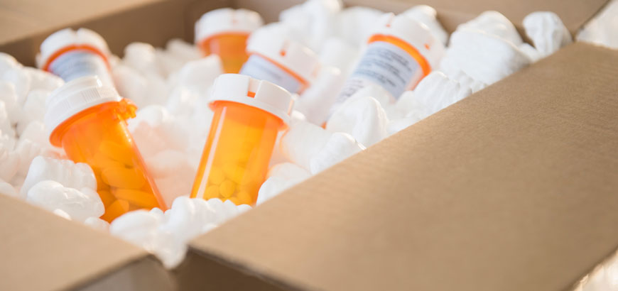 An image of pill bottles floating in styrofoam packing peanuts inside a shipping box