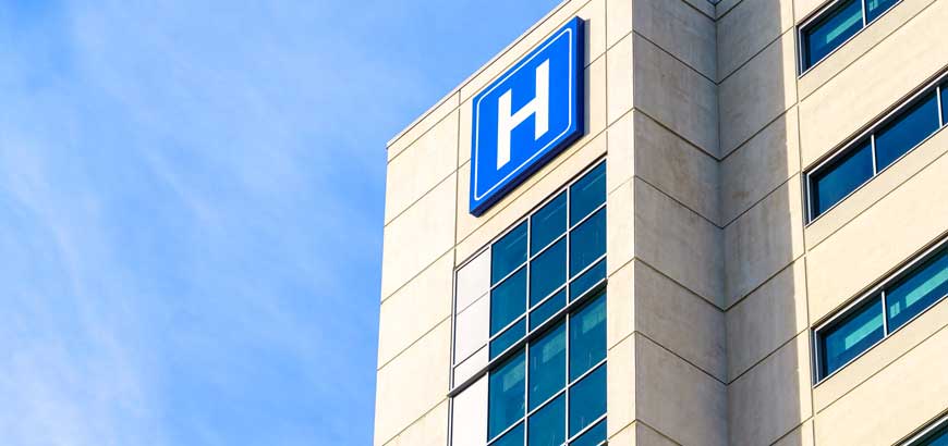 Exterior of a hospital building with a large H symbol on it.