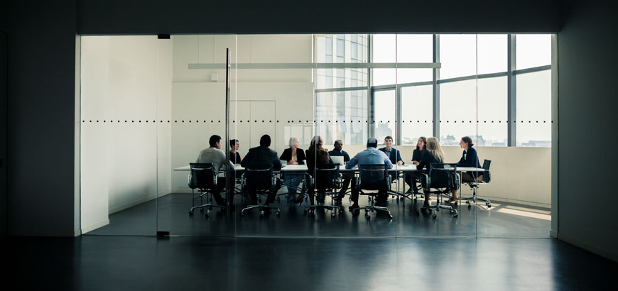 A group of people in a conference room, sitting around a large conference table