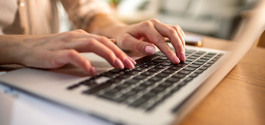 Close up of a woman's hands on a laptop keyboard
