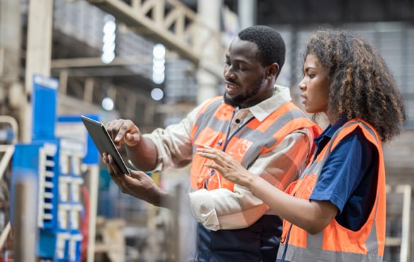 A man and woman looking at a tablet in a warehouse.