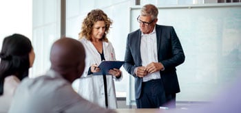 A group of healthcare professionals meet inside a conference room.