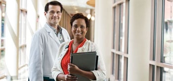 Two hospital workers stand together in a hallway