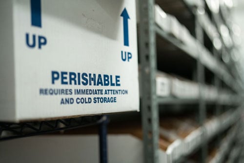 Close up of box that reads "Perishable" on shelf in distribution center