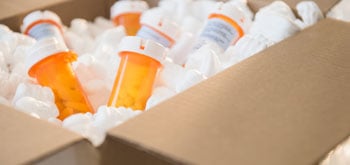 A cardboard box full of packing peanuts and prescription pill bottles