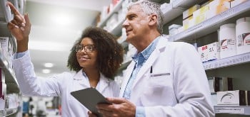 Two pharmacists speaking to each other inside a pharmacy