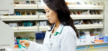 A pharmacist looks over paperwork behind the pharmacy counter