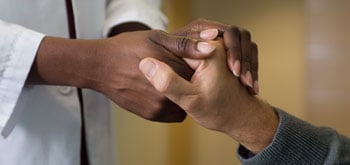 A doctor holds a patient's hand.