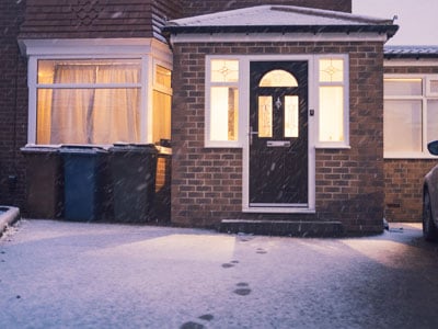 The front door and porch of a house, covered in snow.