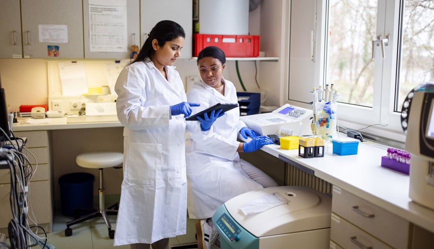 Two health system techs working together in a lab