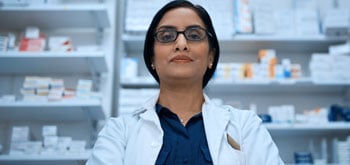 A pharmacist stands with her arms crossed