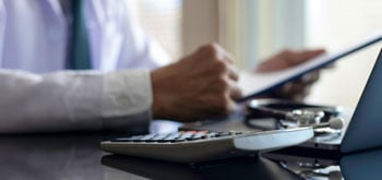 Close up of executive's hands holding a piece of paper while a calculator sits nearby on his desk