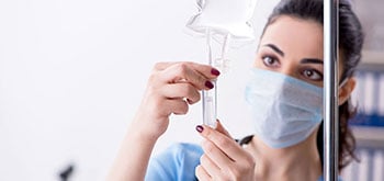 A nurse adjusting a valve on an IV bag