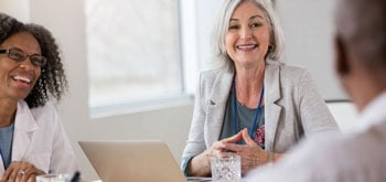 Healthcare professionals sitting around a conference table and smiling