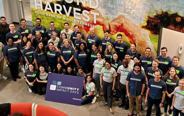 Group of people wearing McKesson shirts holding a "Community Impact Days" sign.