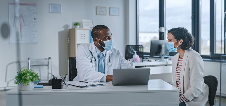 A pharmacist and a customer gathered around a laptop