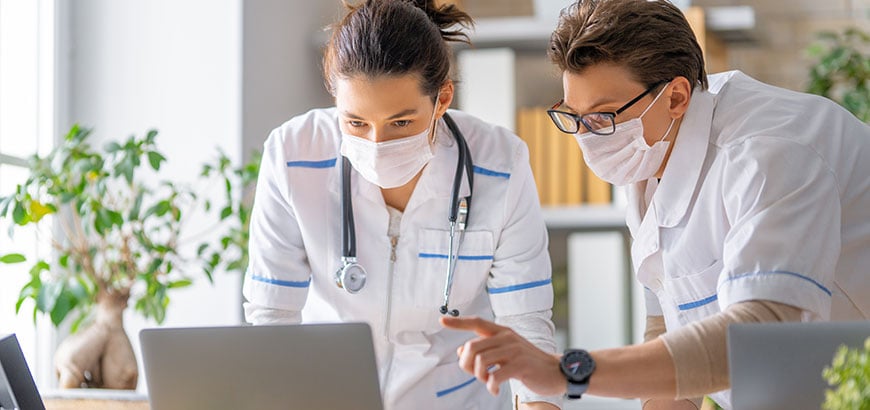 Two doctors speaking while looking at a laptop