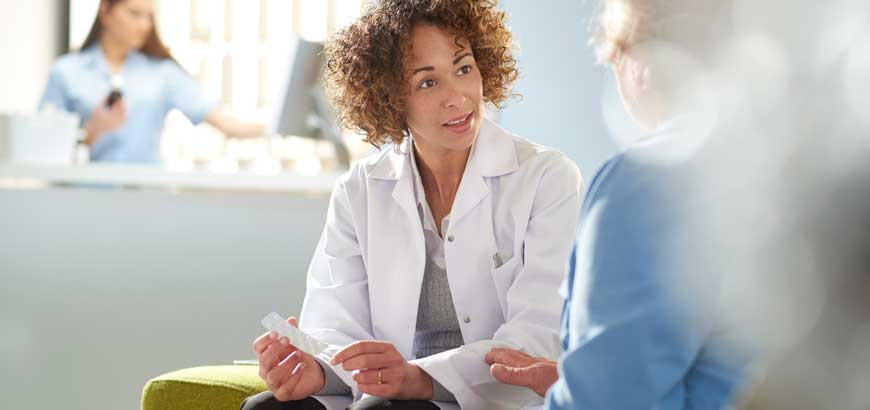 A female pharmacist sits across from a patient