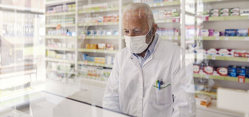 A pharmacist standing behind a pharmacy counter