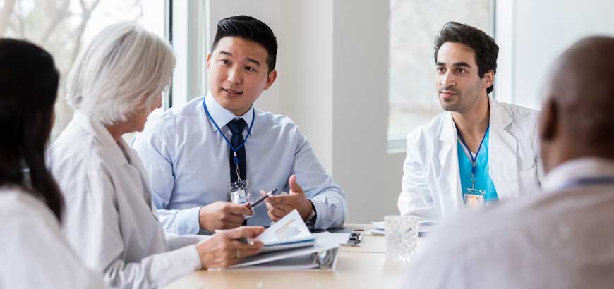 A group of doctors sit in a meeting at a conference table