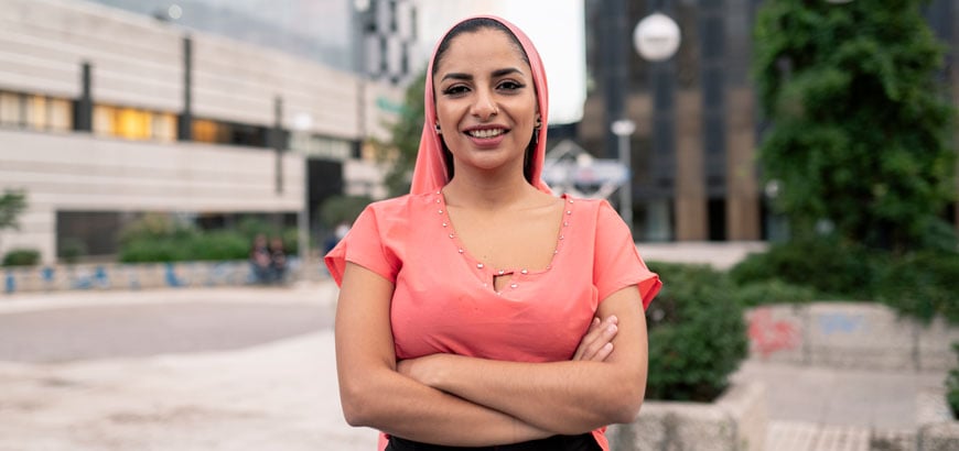 <span>Women standing outside, smiling with her arms crossed</span>