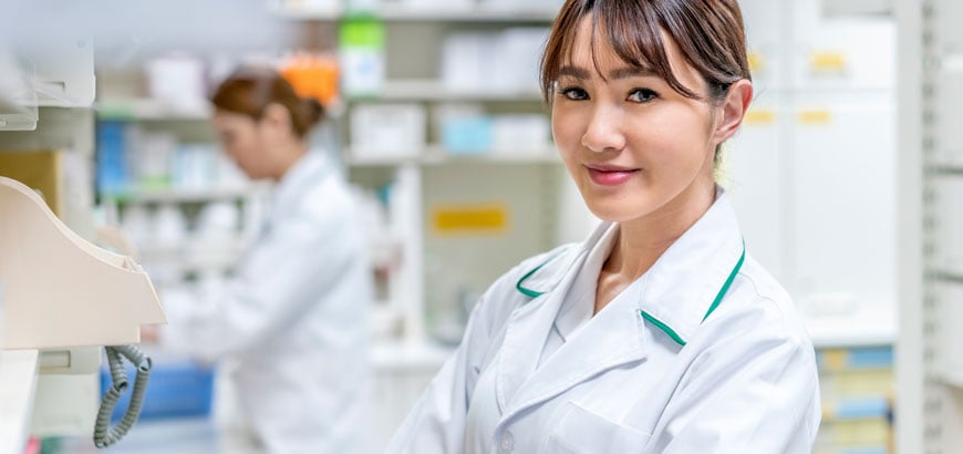 <span>A female pharmacist smiles from a work room in pharmacy </span>