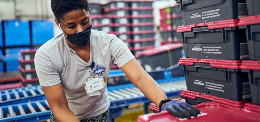 A person handling shipping crates in a McKesson distribution center