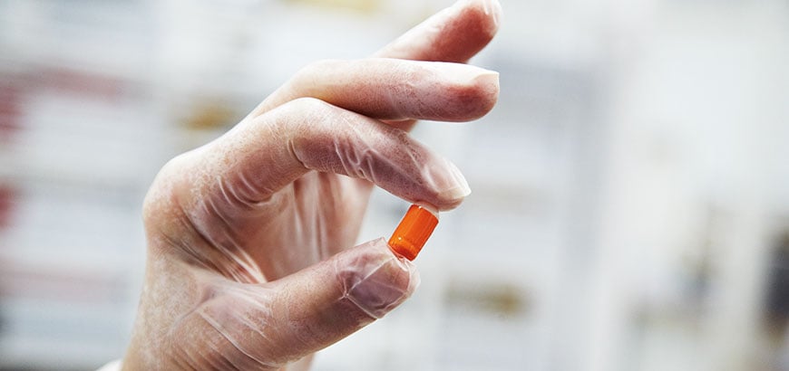 A person holding up a pill