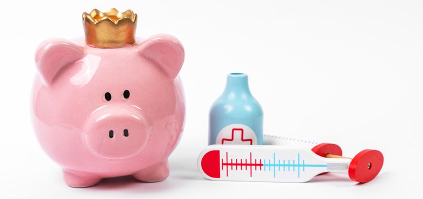 A piggy bank next to a toy syringe and toy medicine bottles