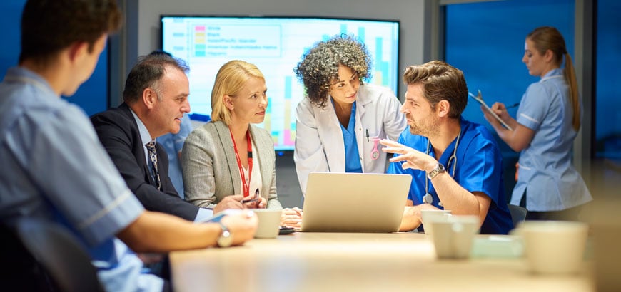 <span>Hospital group of healthcare professional and business people meet around a conference table</span>