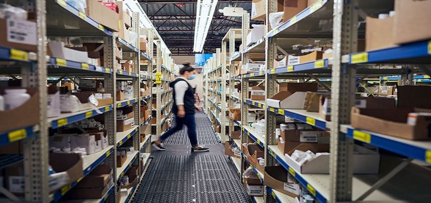 A worker walking through the aisles of a distribution warehouse