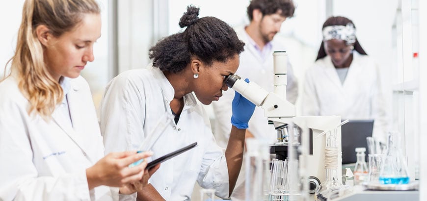 Healthcare workers looking through a microscope in a laboratory