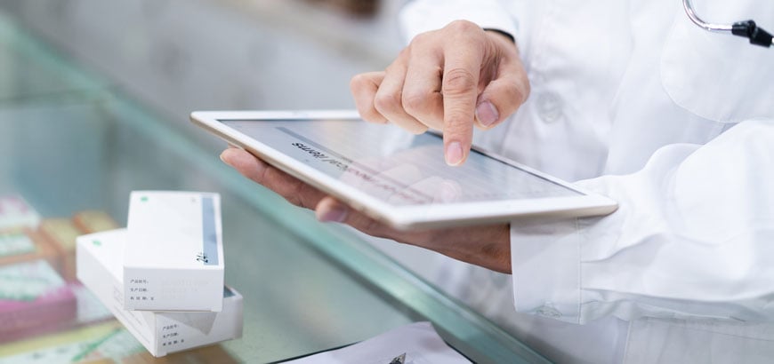 A pharmacist uses a tablet to check in medications to a computer system