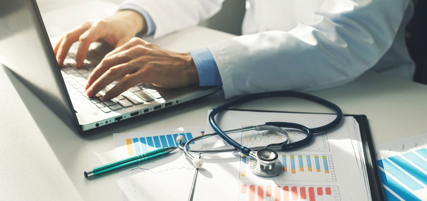 Close up of doctor's hands working with paper containing medical statistics and financial reports