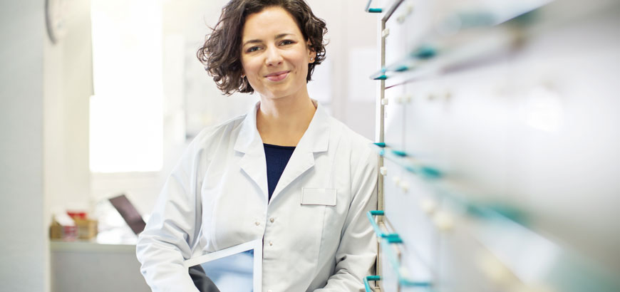 <span>Portrait of confident young female pharmacist leaning to a medicine shelf with a digital tablet</span>