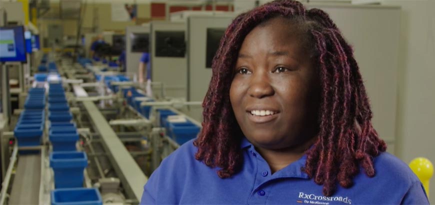 A person speaking in front of an assembly line in a distribution center