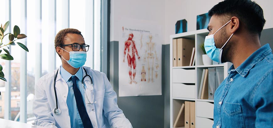 A doctor speaking with a patient while both wearing masks