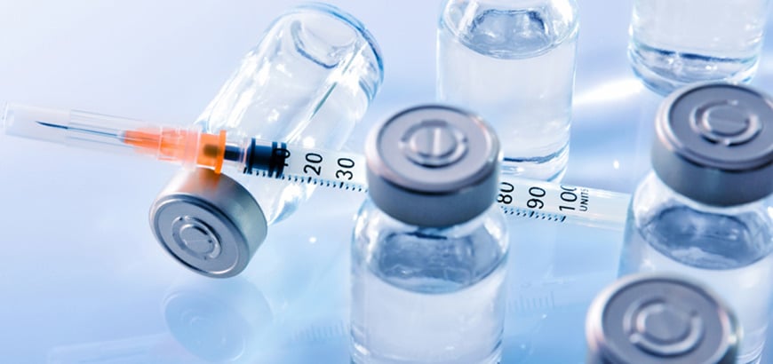 A syringe on a table next to medicine vials