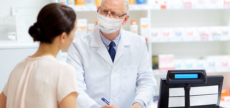 A pharmacist speaking with a customer at a cash register