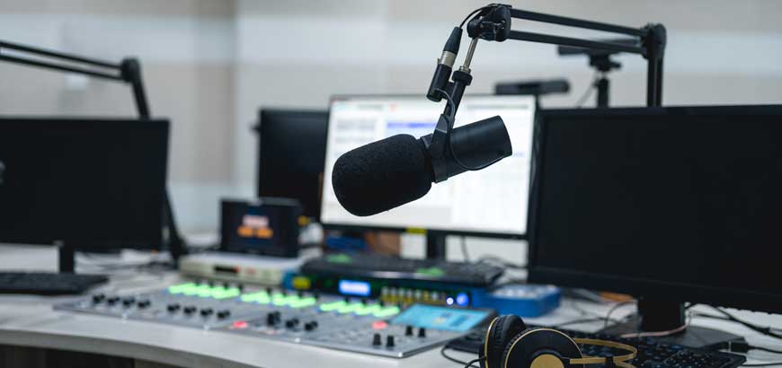 Podcast microphone next to a computer and headphones