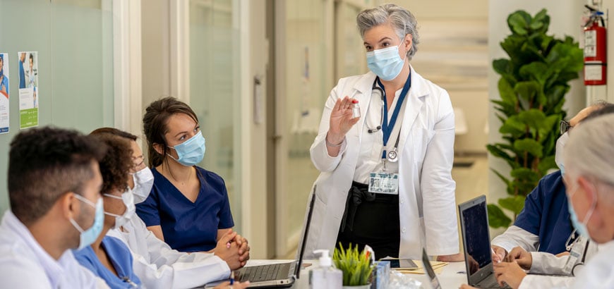 Medical staff meeting at a conference table as a female doctor speaks