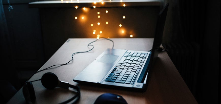 A laptop on a desk with a mouse and headphones nearby.