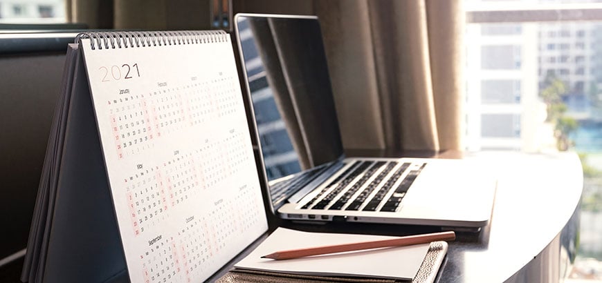 A calendar and a laptop sitting on a desk