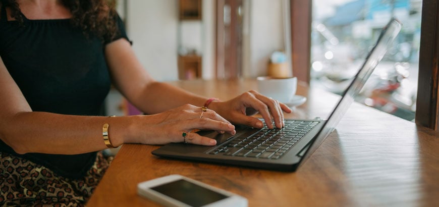 A woman sits at a desk looking at a laptop computer