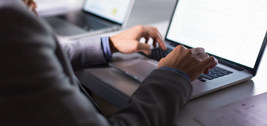 The back of a man's head and hands as he uses a computer<br>  