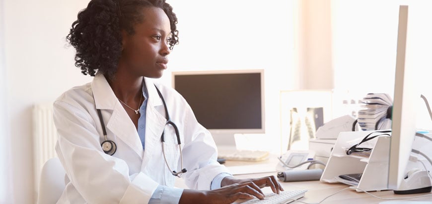 Female doctor typing on her keyboard while looking at her computer screen