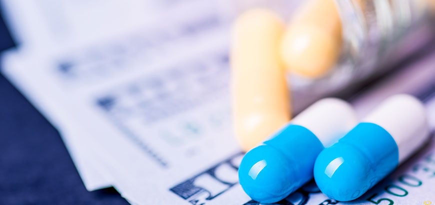 Closeup of two pills lying on paper money bills