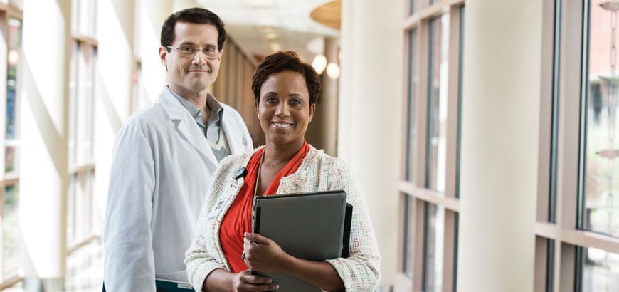 <span>female hospital administrator and male doctor standing in hospital hallway  </span>