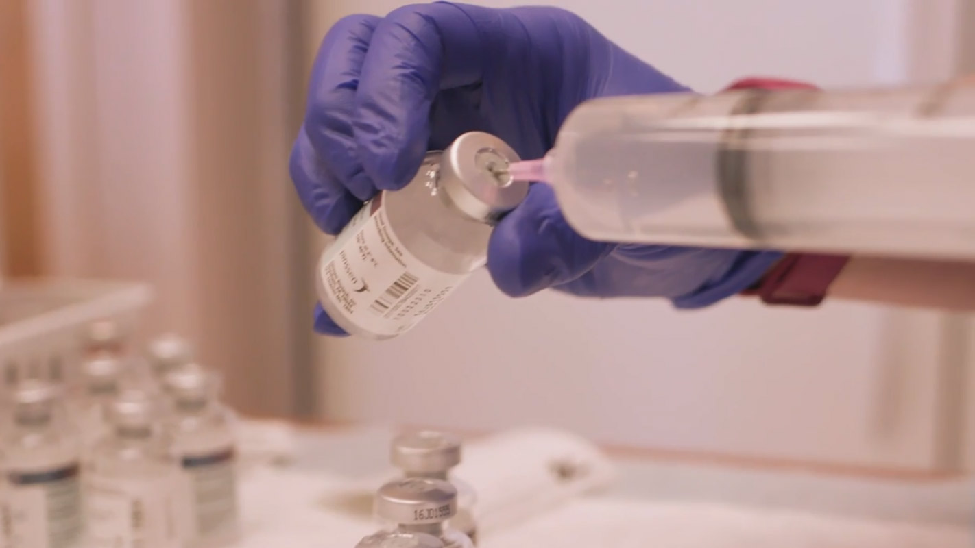 A doctor drawing medicine into a syringe from a vial