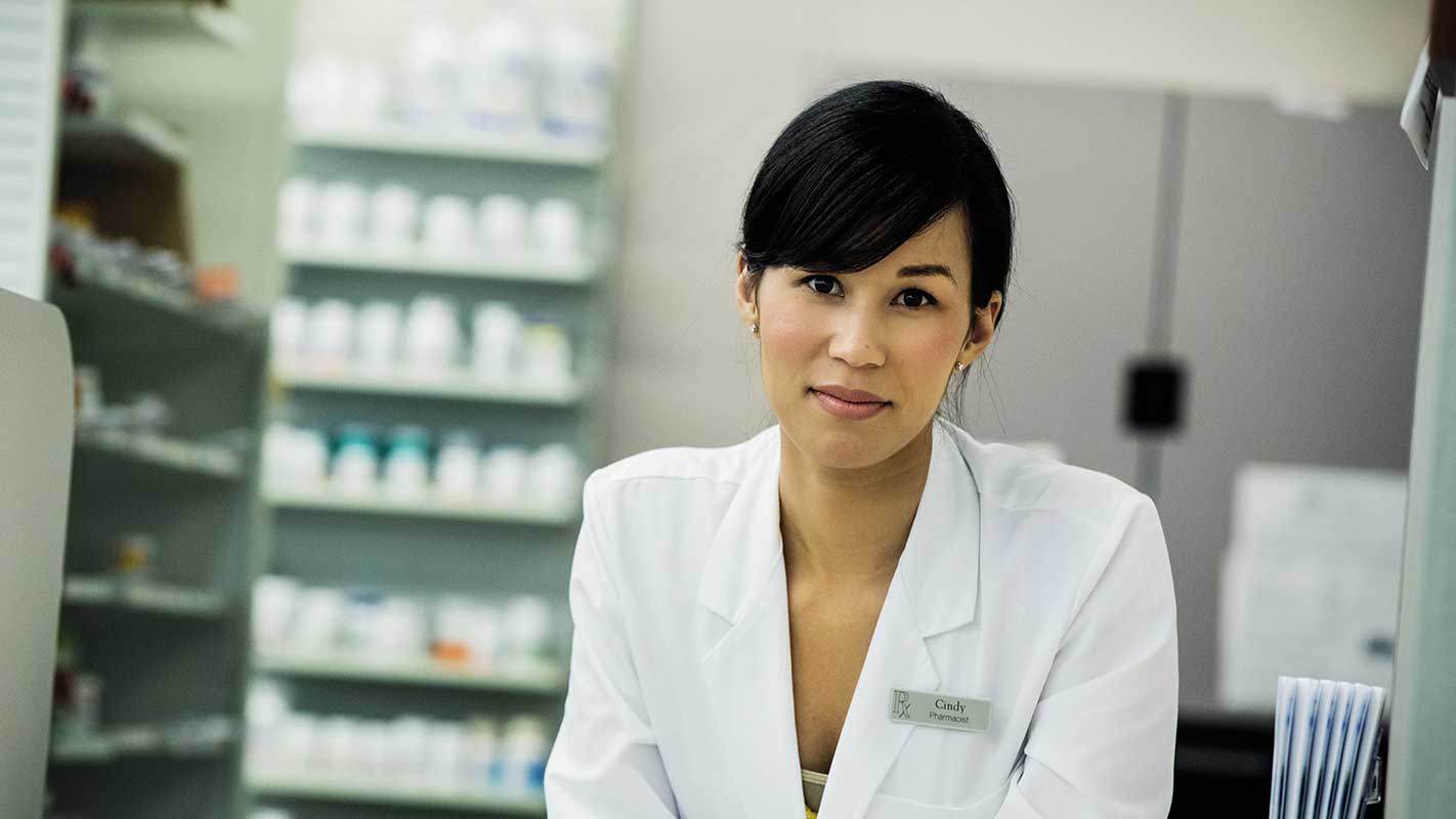 A closeup of a pharmacist sitting in a pharmacy